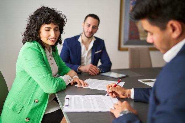 Businessman signing contract with a businesswoman and a businessman observing in meeting room